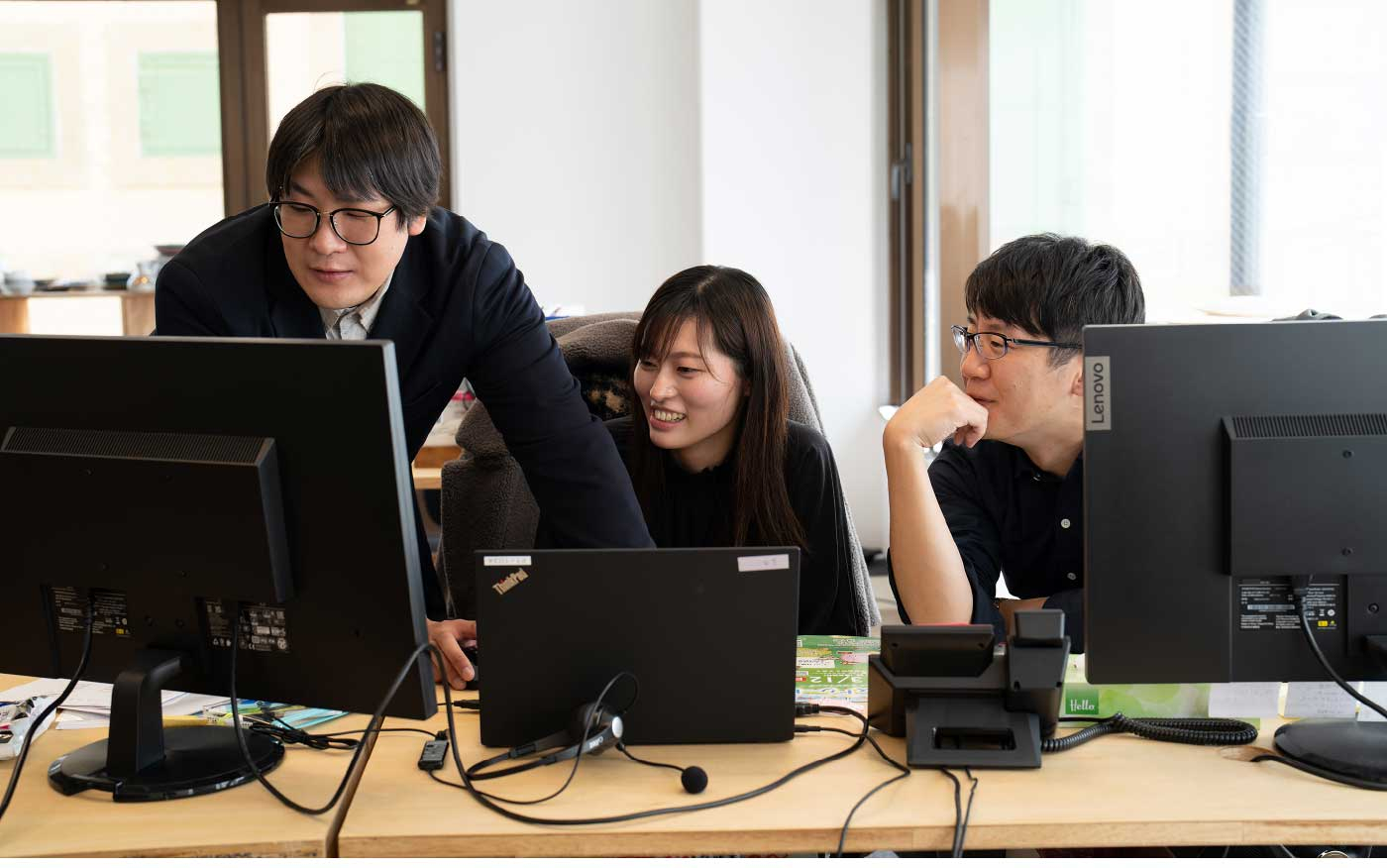 パンクチュアルの社員がパソコンの前で楽しそうに話し合っている写真