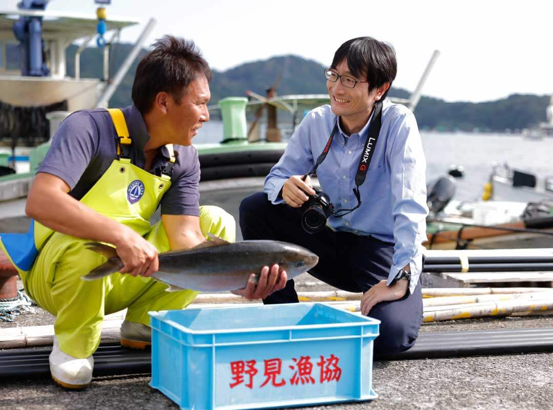 パンクチュアルの社員と漁師さんが笑っている写真