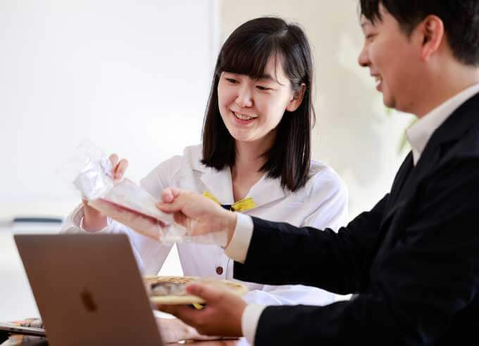 パンクチュアルの社員と女性がパソコンの前で商品を見せて笑っている写真