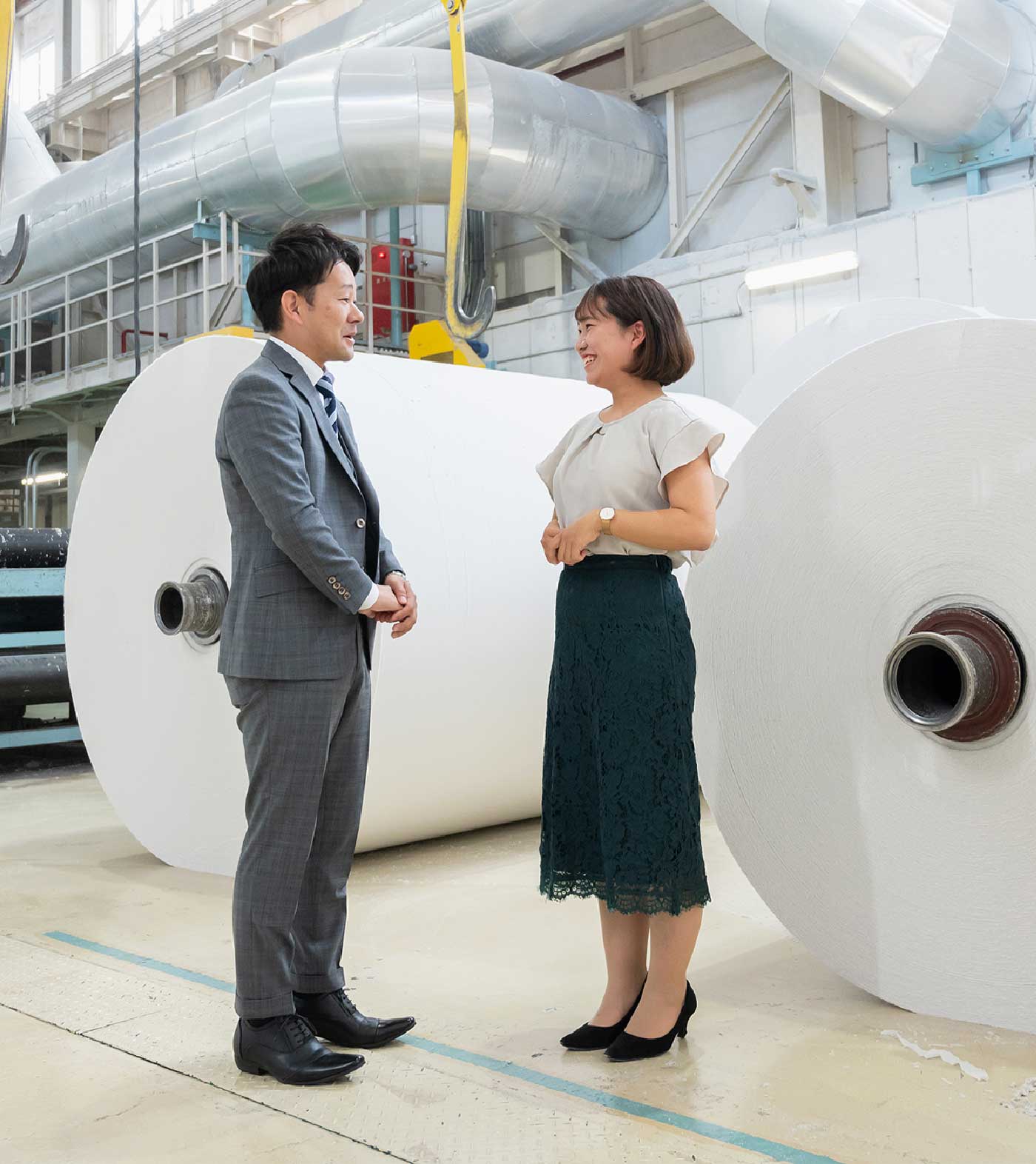 工場ではなすスーツを着た男性と女性