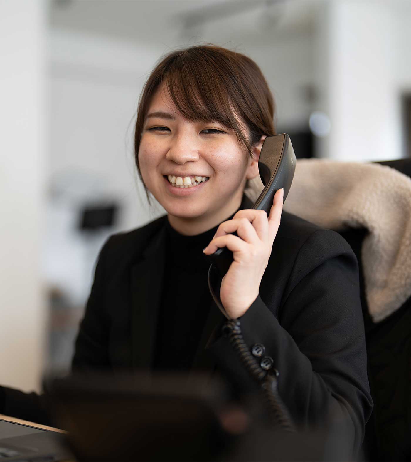 受話器を持って笑っているパンクチュアルの女性社員