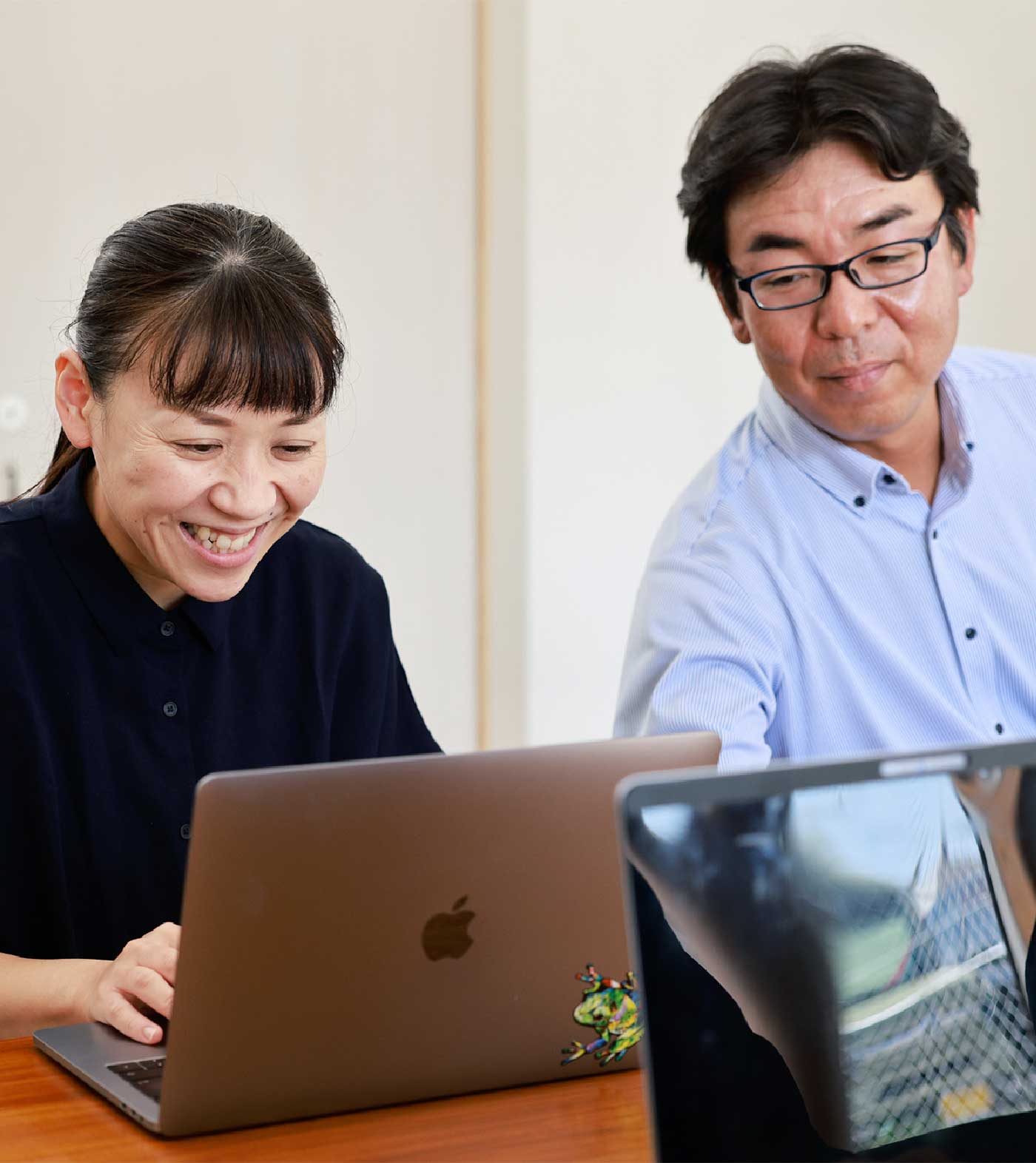 パソコンをしながら笑っている社員二人